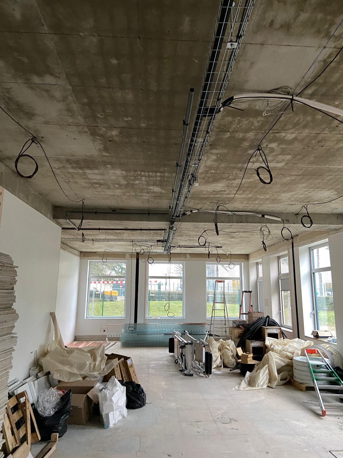 Chemin de câbles et attentes électriques au plafond d’un local en travaux