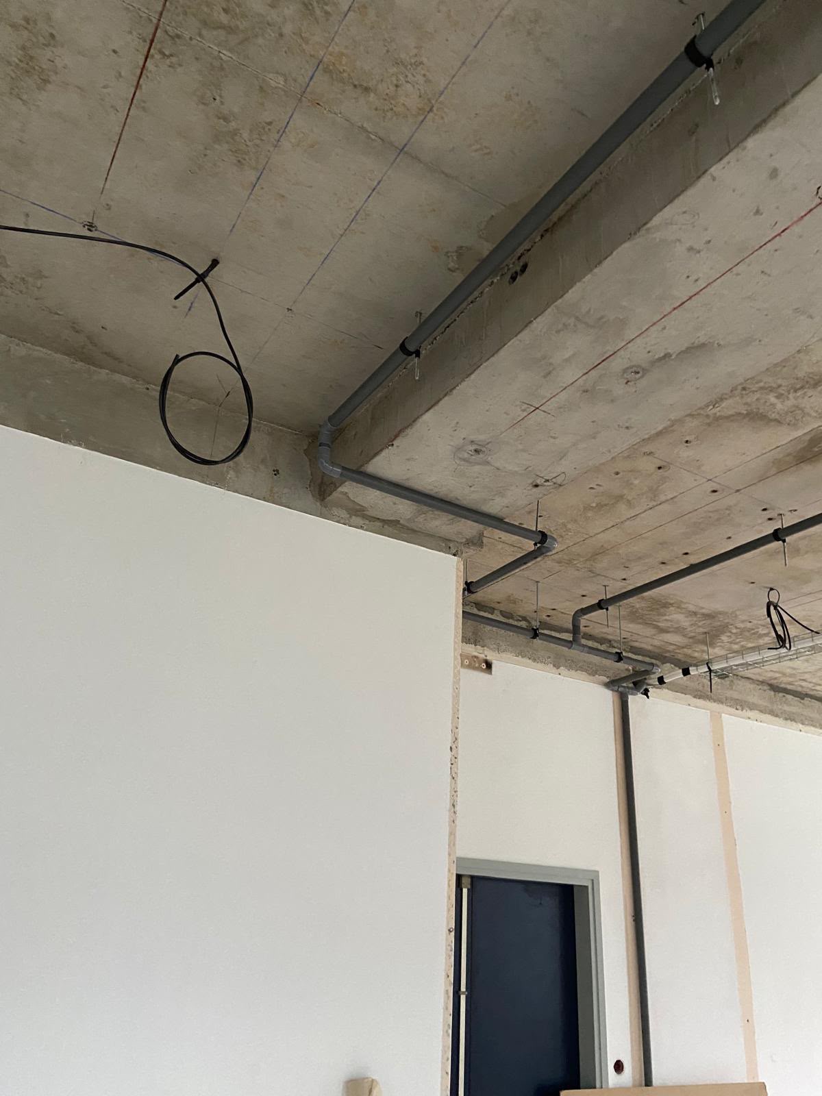 Gaines électriques posées le long de cloisons et d’un plafond en béton